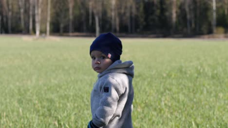 Back-of-pensive-disoriented-toddler-walking-in-rural-spring-field