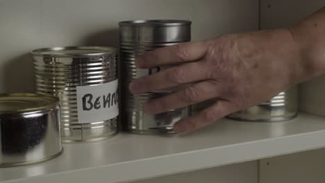 Getting-tins-of-aluminum-baked-beans-out-of-food-cupboard-shelf