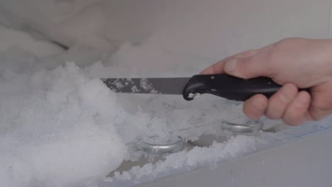 Defrosting-refrigerator-using-knife-to-clear-away-ice