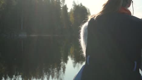 Woman-paddling-canoe-on-beautiful-lake-in-autumn,-rear-view-closeup-slow-motion-1