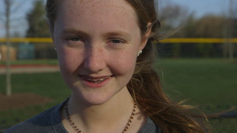 Closeup-Portrait-Eines-Teenie-Mädchen-Athleten,-Der-Draußen-Auf-Einer-Strecke-In-Die-Kamera-Lächelt