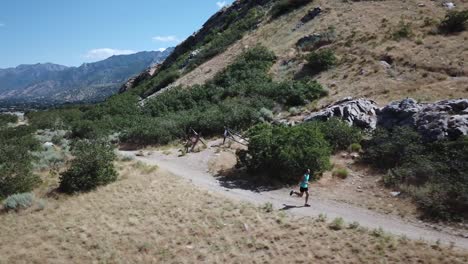 Drone-Shot-following-an-active-man-running-on-the-outdoor-Wasatch-Mountain-trails-above-Draper-City,-Utah-1