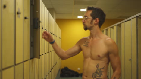 Male-Swimmer-gets-out-from-changing-room-and-put-his-bag-in-electronic-locker