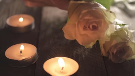Hand-placing-pink-and-white-blossoming-roses-with-tea-light-candles