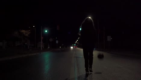 Teenage-girl-in-black-sweater-dribbling-basketball-down-the-yellow-line-of-a-wet-city-street-at-night-with-headlights-in-distance