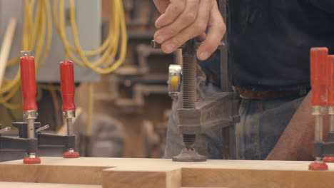 A-carpenter-tightens-a-vice-holding-boards-of-wood-together-in-slow-motion