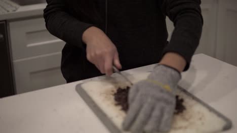 A-young-Korean-girl-cuts-up-dark-chocolate-before-melting-it-for-millionaire-shortbread-cookies-while-wearing-safety-gloves-1