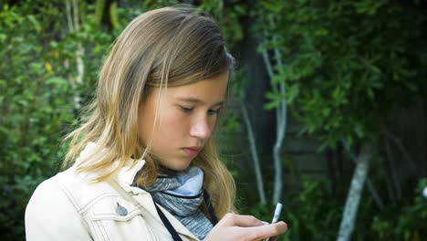 An-attractive-teenage-girl-checks-social-media-messages-on-her-smartphone-in-the-garden