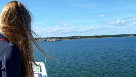 Static-view-behind-a-blonde-haired-woman-on-a-ship-with-her-hair-being-blown-about-on-a-ferry-crossing-from-Uugu-nature-park-to-the-mainland-of-Estonia-on-the-Baltic-Sea
