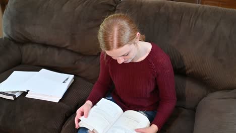 High-school-student,-Madelyn,-studies-from-a-textbook,-looks-up-at-the-camera-with-a-huge-smile