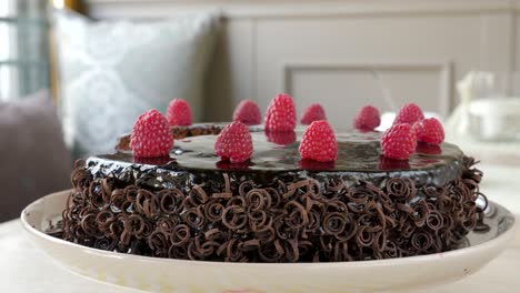 Chocolate-raspberry-cake-topped-with-fresh-raspberries-and-garnished-chocolate-spirals-rotating-clockwise
