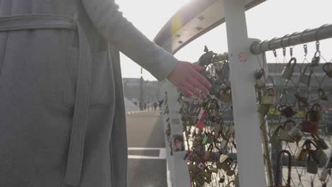 Young-female-tourist-touches-the-love-locks-on-a-bridge-in-the-morning-sun