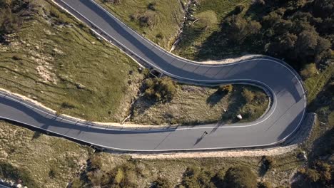 Aerial-top-View-of-a-Skater-Practicing-Downhill-down-a-Road-in-the-Middle-of-the-Forest-in-Andorra---Europe