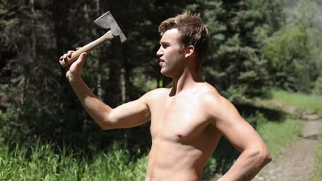 Shot-of-a-shirtless-man-practicing-his-axe-throwing-skill-by-trying-to-throw-his-hatchet-at-a-pine-tree-1