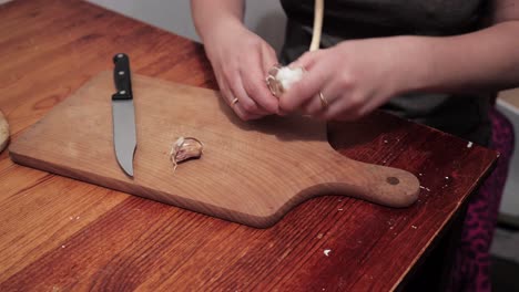 Woman's-hands-are-starting-to-peel-garlic-on-a-chopping-board