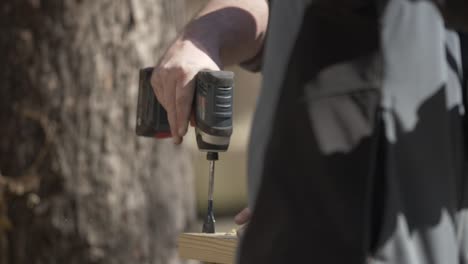 A-man-uses-a-drill-to-drill-hole-into-board