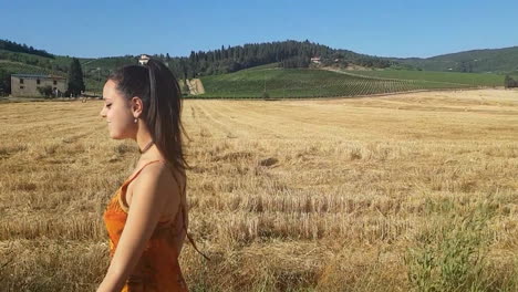 Young-brunette-girl-walking-near-a-wheat-field-at-the-beginning-of-summer-while-singing