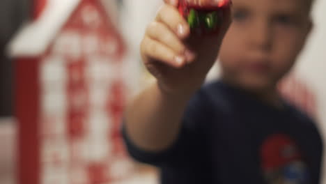 Close-Up-Hands-Little-Boy-Hold-Snow-Globe-With-Santa-Claus-and-Advent-Calendar-in-the-Blured-Background