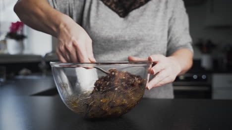 Lady-stirring-mincemeat-pie-filling-in-a-clear-glass-bowl-as-she-bakes-in-her-kitchen