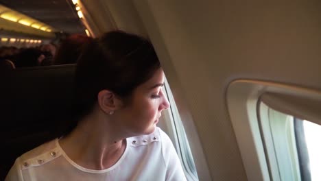 Young-girl-in-the-plane-looks-through-the-window