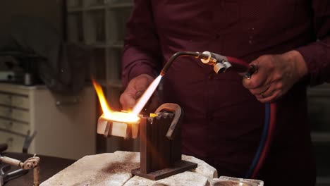 Pouring-molten-gold-into-a-metal-mould-while-heating-it-with-a-gas-torch