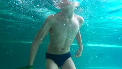 Young-boy-is-diving-happily-underwater-at-indoor-swimming-pool