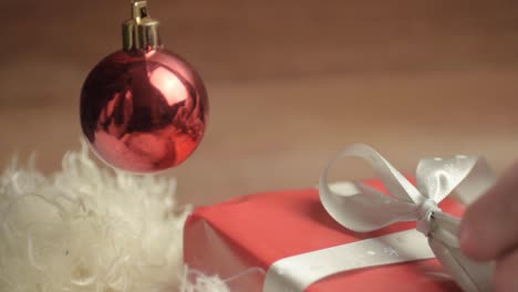 Auspacken-Eines-Weihnachtsgeschenks-Mit-Rotem-Papier-Und-Schleife-Mit-Roter-Kugel
