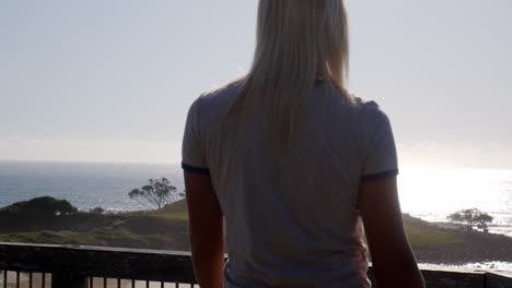 Female-walking-onto-balcony-platform-overlooking-ocean-sea-view-landscape