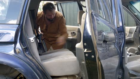 Man-vacuuming-inside-of-SUV-cleaning-vehicle-out-after-road-trip