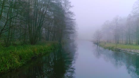 Sailing-along-a-dark-misty-river,-in-the-middle-of-the-forest
