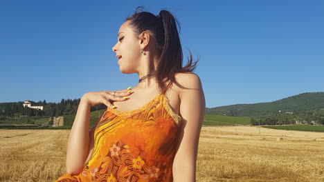 Young-brunette-girl-singing-towards-camera-in-a-wheat-field-at-the-beginning-of-summer