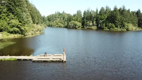 Sitting-on-a-dock-while-flying-a-drone-over-Cullaby-Lake,-Oregon