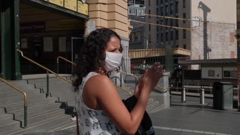 Frau-Mit-Maske,-Die-Während-Des-Weltweiten-Covid19-ausbruchs,-Melbourne-Australien,-Desinfektionsmittel-Aufträgt