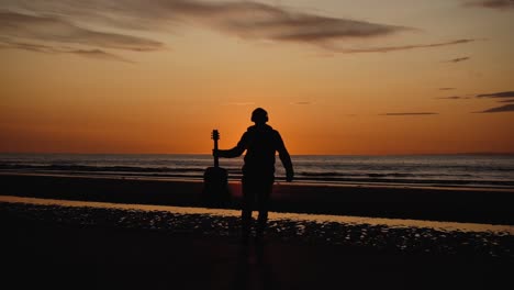 Man-running-with-guitar-in-back-sand-beach-at-sunset-34