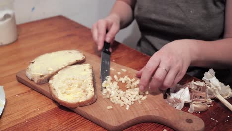 Woman's-hands-puts-garlic-on-a-slice-of-bread-spread-with-butter