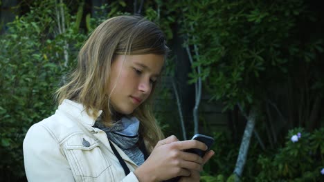 An-attractive-teenage-girl-checks-social-media-messages-on-her-smartphone-in-the-garden-1