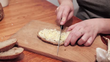 Woman's-hands-with-salt,-then-cut-a-slice-of-bread-smeared-with-butter-and-garlic-on-a-chopping-board
