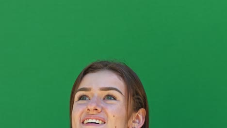 Close-up-smiling-girl's-head-against-green-screen-looking-up-and-around
