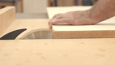 Craftsman-cuts-wood-boards-with-table-saw-in-slow-motion-close-up