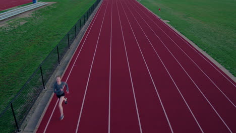 Teen-girl-running-track-runs-towards-and-under-aerial-camera