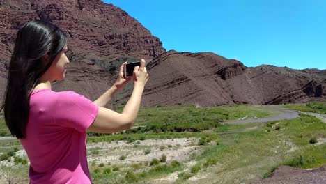 A-young-woman-uses-her-phone-to-take-photos-of-the-Quebrada-de-Cafayate-in-Argentina