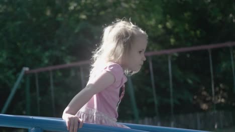 Closeup-of-a-4-years-old-girl-in-slow-motion-on-top-of-a-structure-in-a-playground