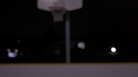 Girls-shoots-basketball-at-net-at-night-and-it-gets-stuck