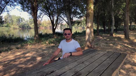 Man-sitting-at-a-wooden-table-in-the-forest
