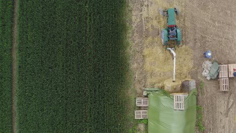 Aerial-shot-of-tractor-taking-a-haystack-to-prepare-cereal-straw-for-strawberries
