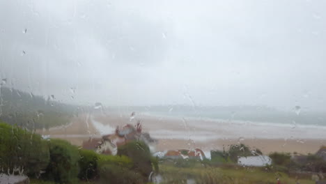 Raindrops-Falling-against-a-Window-with-an-Ocean-View-in-Slow-Motion