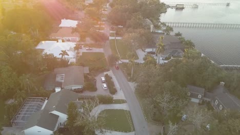 Luftaufnahme-Eines-Roten-Sportwagens,-Der-Bei-Sonnenuntergang-Durch-Die-South-Florida-Street-Fährt,-Mit-Dem-Fluss-Auf-Der-Rechten-Seite-1