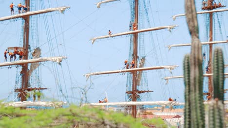 Sailors-working-on-the-mast-sheets,-sails,-and-rigging-while-the-ship-is-moored-at-the-Port-in-Curaçao