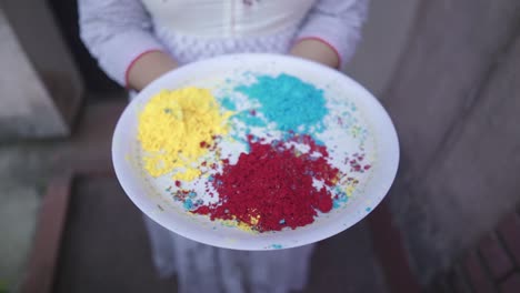 Unrecognizable-girl-holds-tray-of-colored-powders-on-Holi-outdoor,-slow-motion