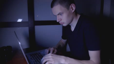 Young-Man-Working-And-Typing-On-His-Laptop-In-The-Dark